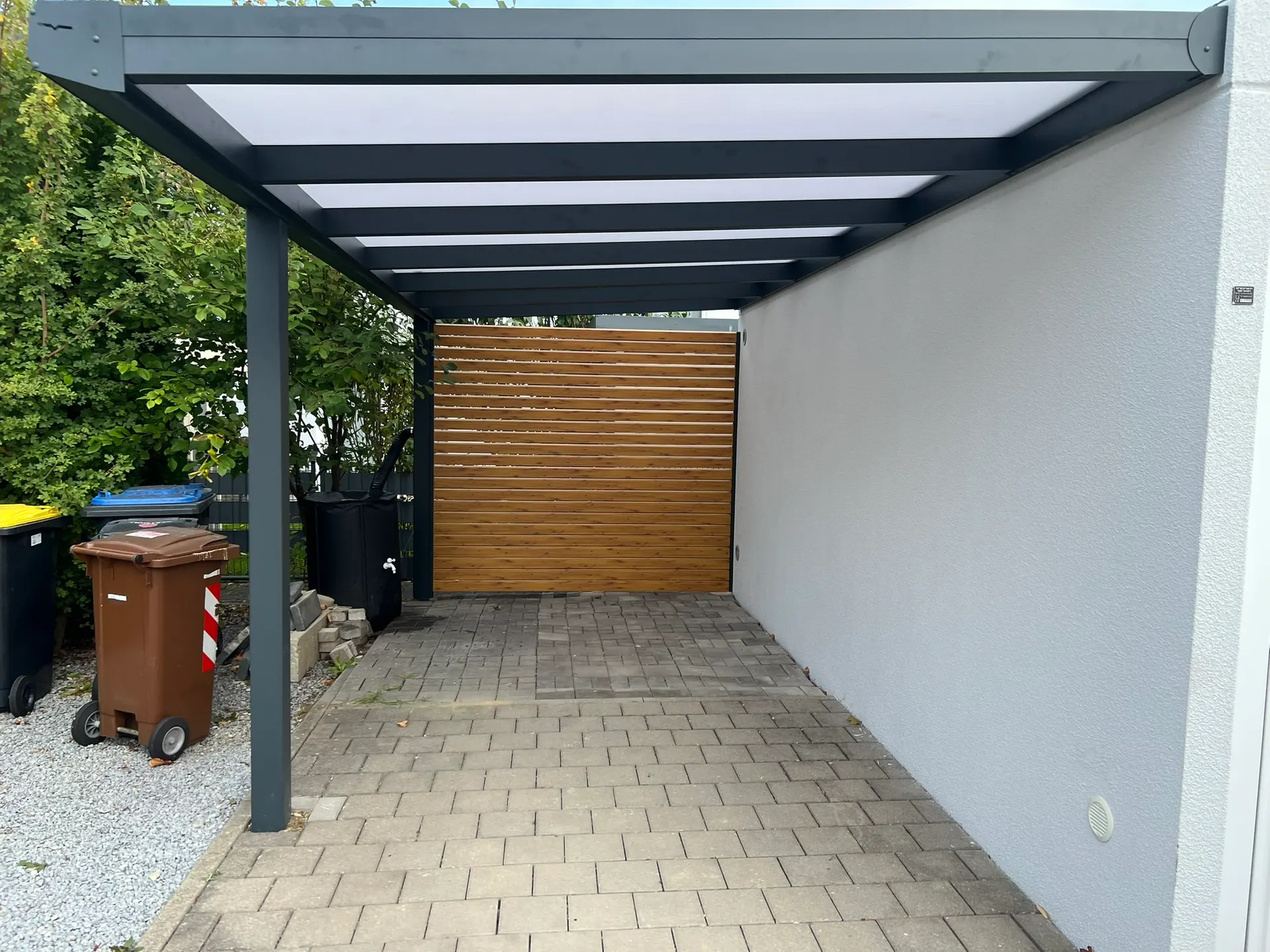Carport mit Wandanschluss aus Aluminium in Gersthofen mit Polycarbonat-Dach und Seitenwand in Holzoptik